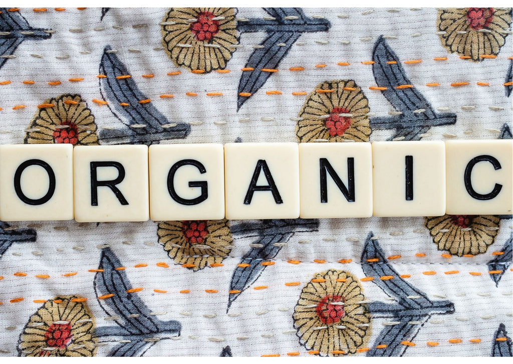 The word Organic spelled out in scrabble tiles on a piece of fabric