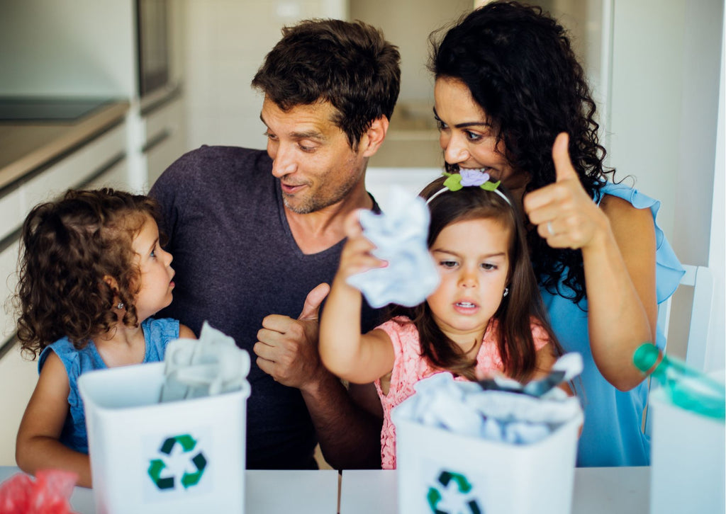 Young couple with children teaching them to recycle