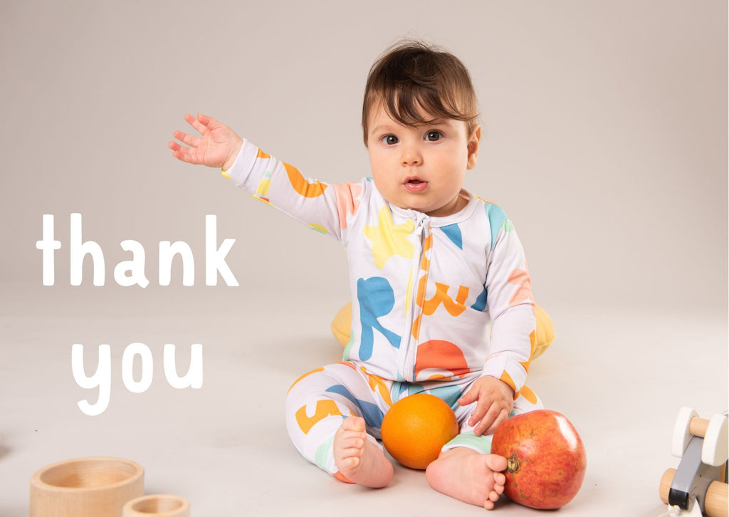 a baby wearing an organic baby romper from Roc + Rudi, and the words thank you