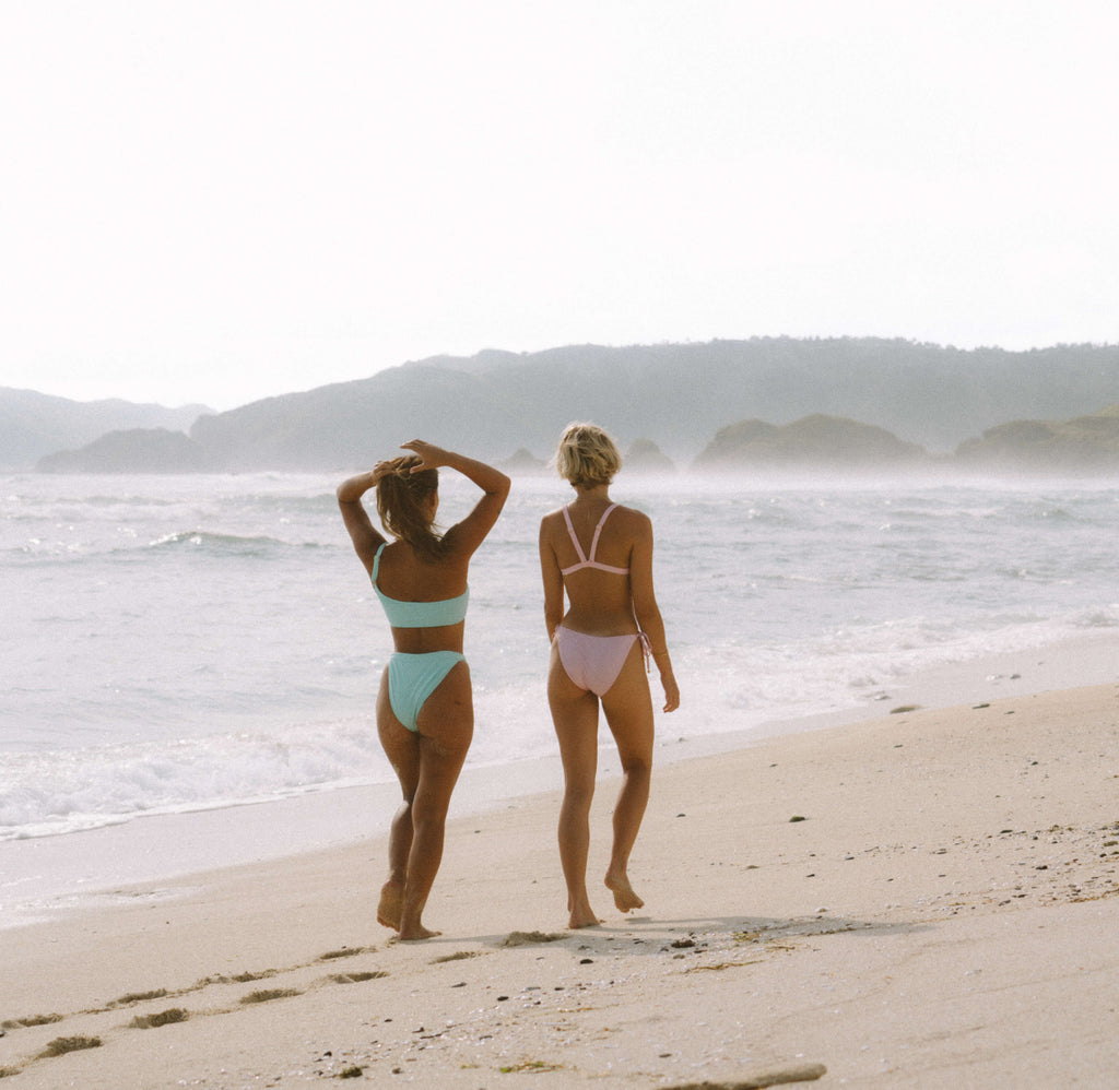 友人や自然とのつながりは、精神的健康を改善するための強力なツールとなり得ます。コラルのサステナブルな女性用ビキニを着てビーチを散歩