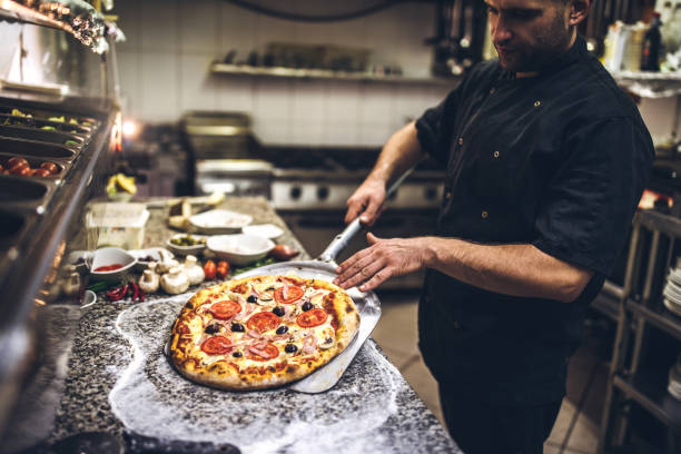 Chef pizzaiolo qui fait une pizza