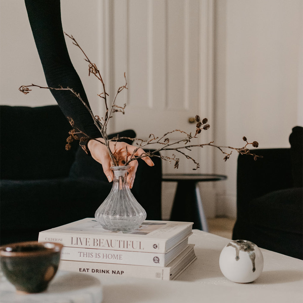 interior designer placing glass vase, mid century living room decor