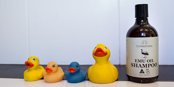 Emu shampoo next to rubber duckies in bathtub