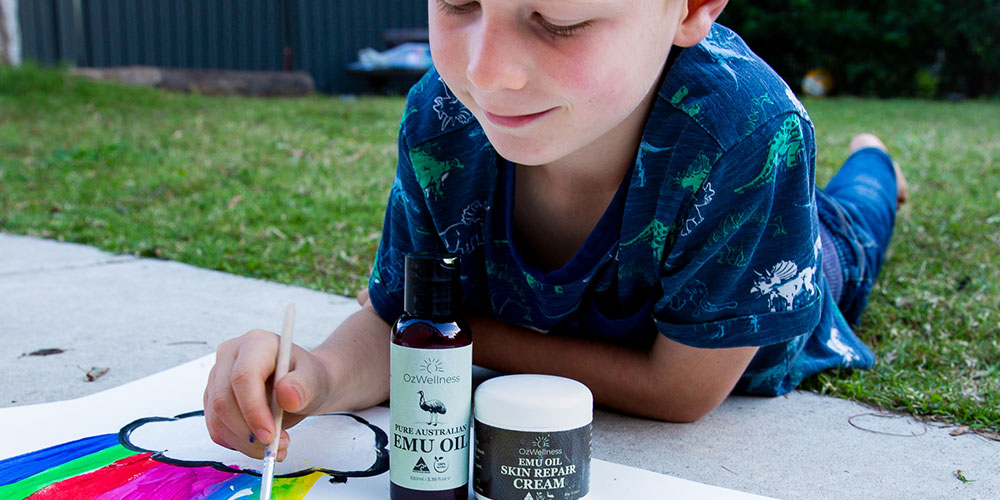 Child drawing in backyard with emu oil bottle
