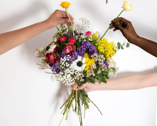 du Pain & des Roses photo emblématique avec des mains tenant des fleurs françaises et de saison sous un bouquet