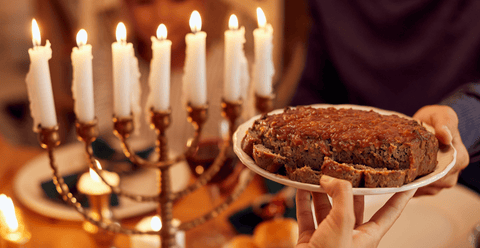 Meatloaf with sauce being passed from one hand to another. Seven candles in the background.