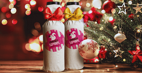 Two Christmas-wrapped Hungry Squirrel sauce with a bow, accompanied by a Christmas tree and ornaments