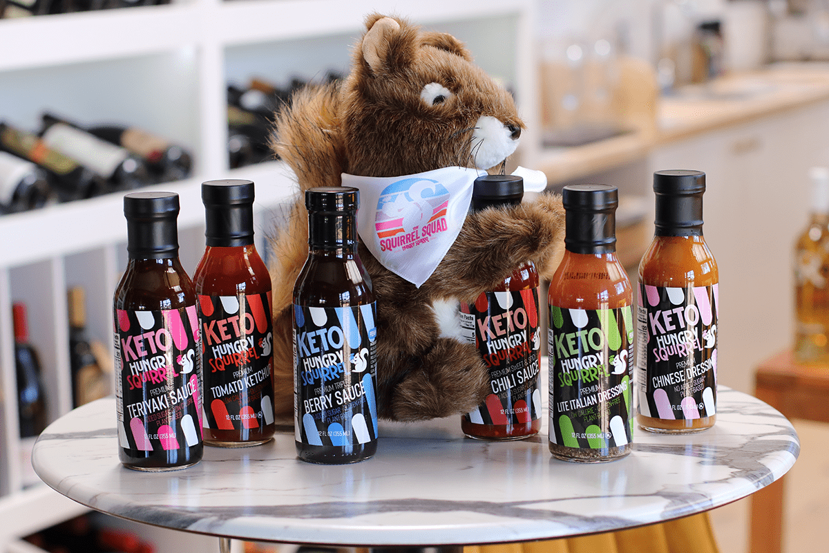 Sammy the squirrel showcasing hungry squirrel sauces and hugging sweet and spicy chili sauce on a table