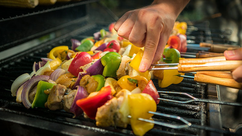 hand putting skewers on the grill