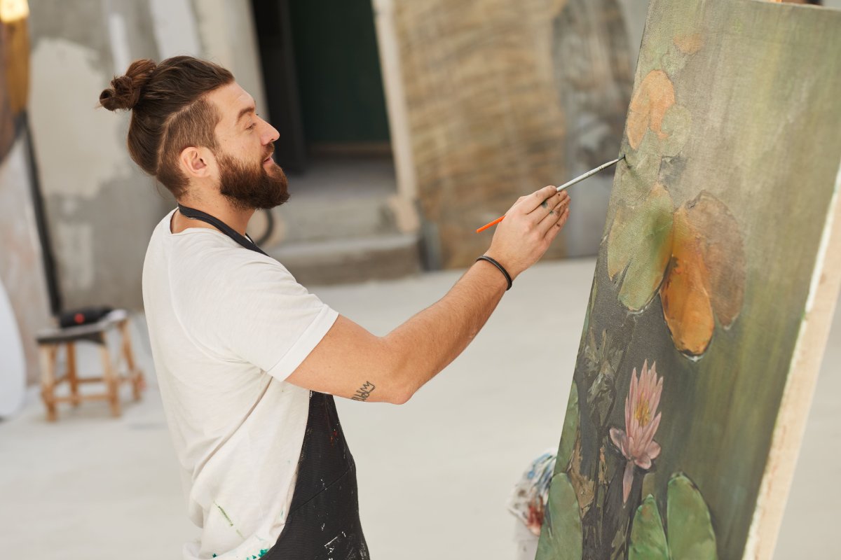 Male artist painting in a studio on a large canvas