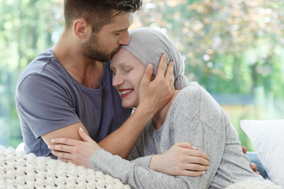 Woman in a headscarf being hugged and kissed on the forehead by their significant other