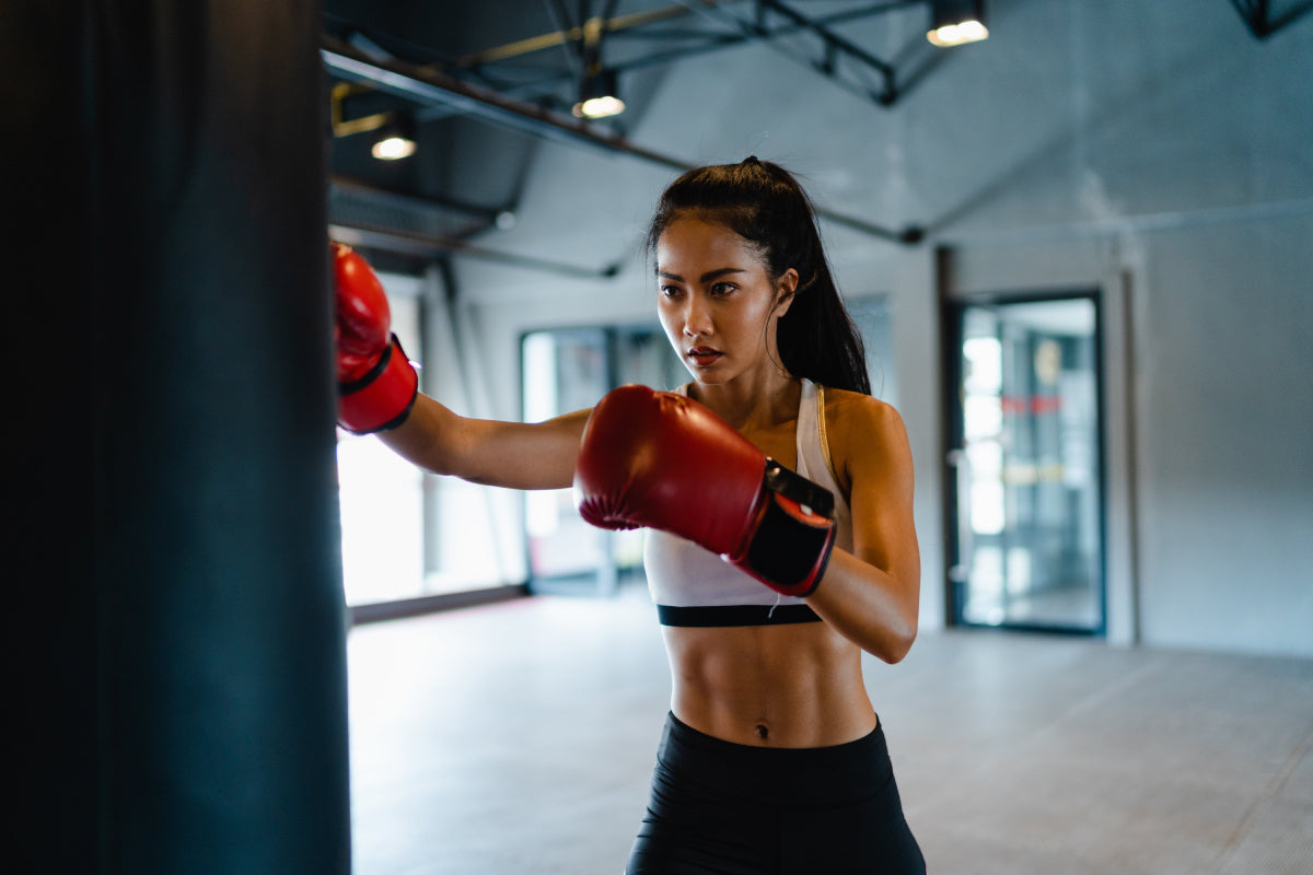 Woman with boxing gloves working out with a punching bag