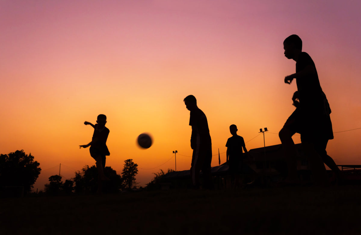 children's silhouettes playing soccer at a park after sun set