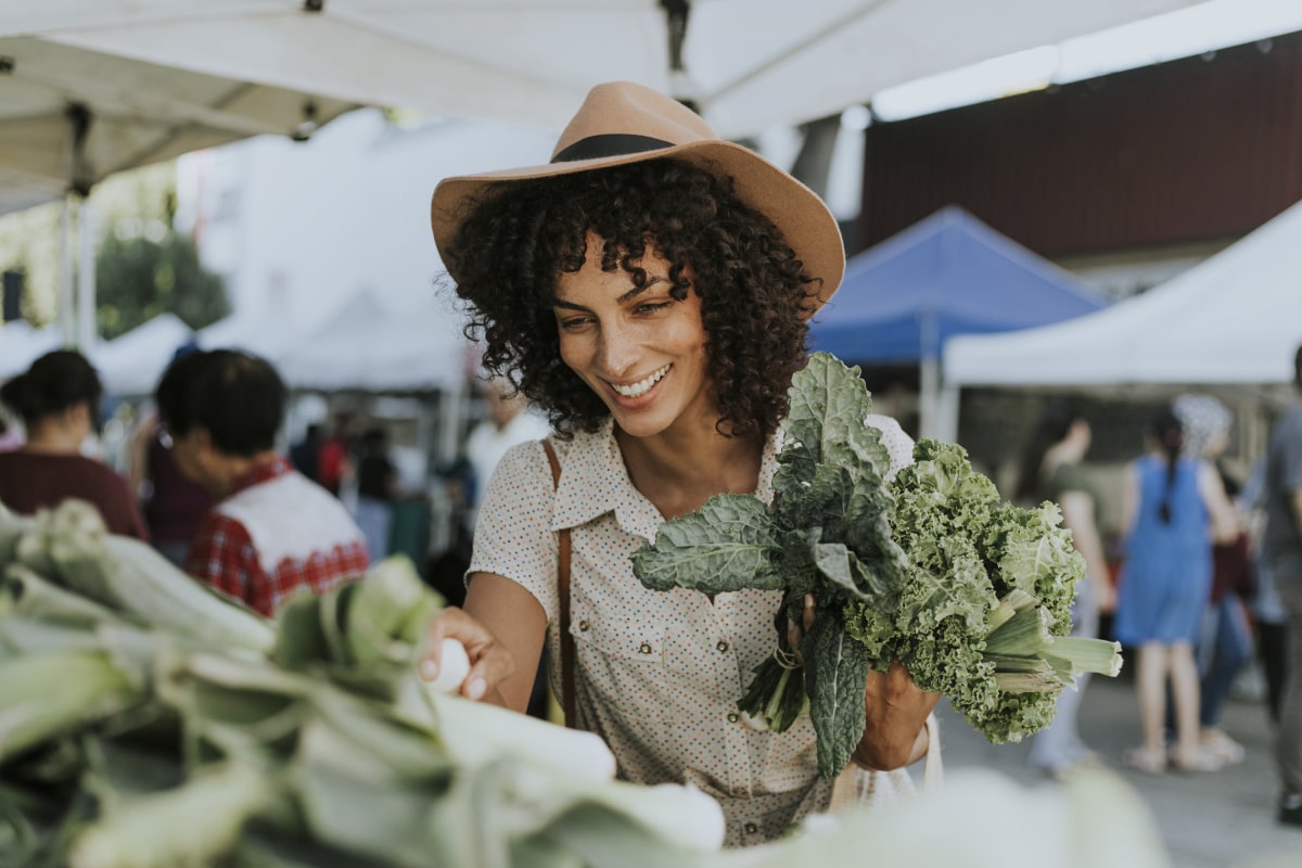 Woman in a hat buying kale at a farmers market