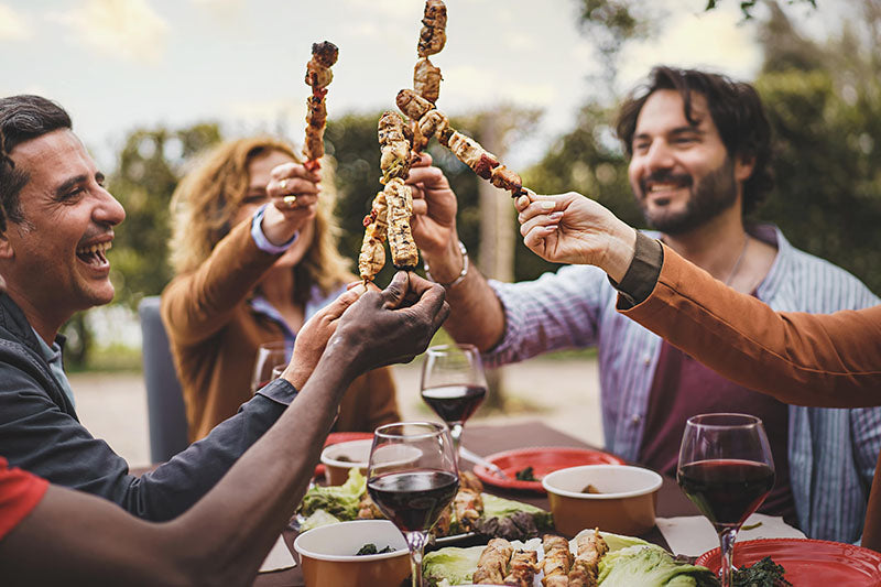 friends dinning outside toasting skewers