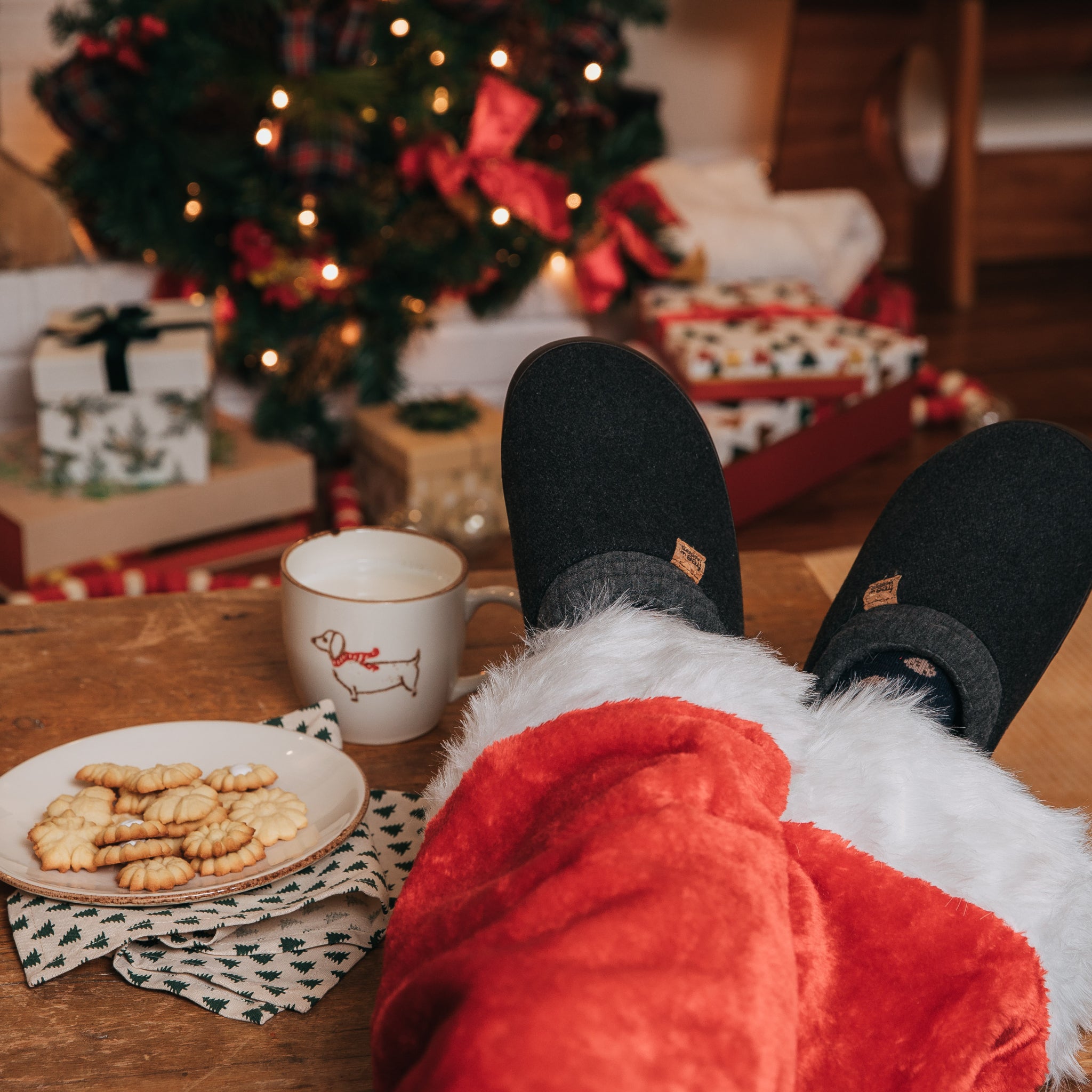 Santa legs with slippers with cookies on the table