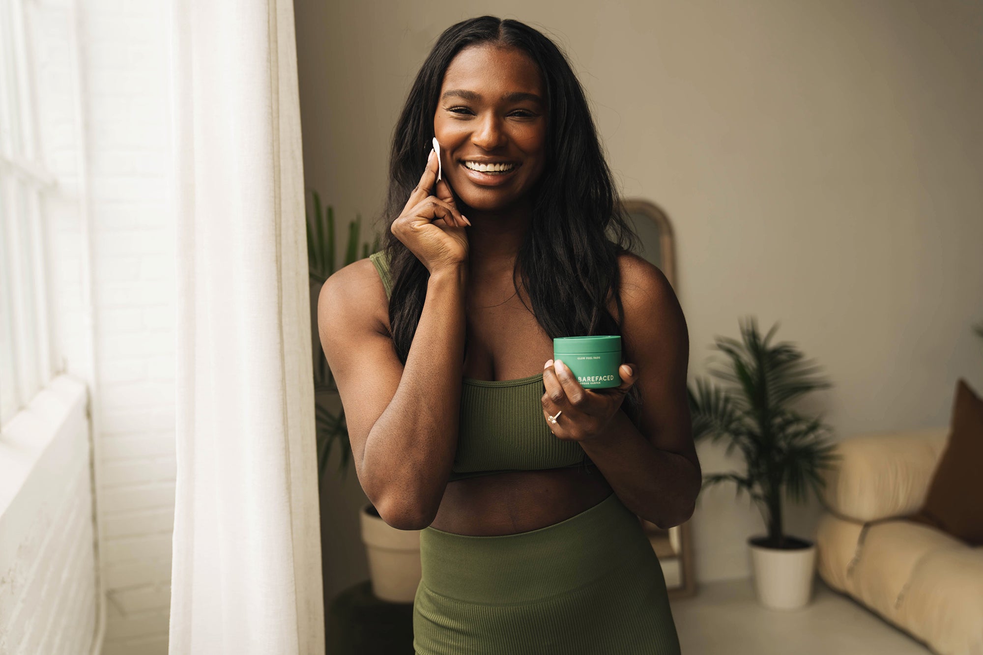 Woman in workout clothes holding Glow Peel Pads