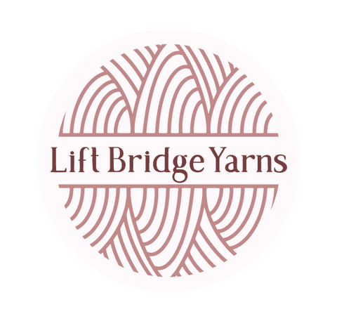 Geometric yarn ball with Lift Bridge Yarns written in serif font in two tone pinks