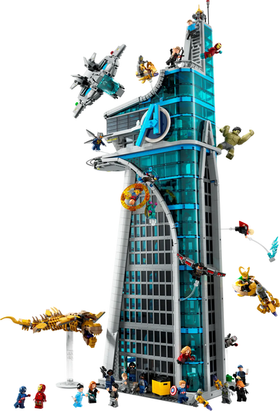 This is an image of the LEGO Avengers Tower set, a tall and detailed skyscraper structure emblazoned with the Avengers 'A' logo. The tower features multiple levels and is adorned with action scenes, including various Avengers like Iron Man, Captain America, and Thor, engaged in battle against villains. There are LEGO Quinjets and other flying vehicles attached to the tower, creating a dynamic and action-packed scene