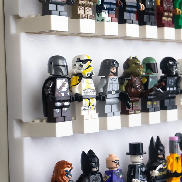 Image of a Lego minifigure display wall: A neatly organized wall-mounted display showcasing a variety of Lego minifigures, including characters resembling Stormtroopers, superheroes, and fantasy figures, each standing on individual white shelves against a soft grey background.