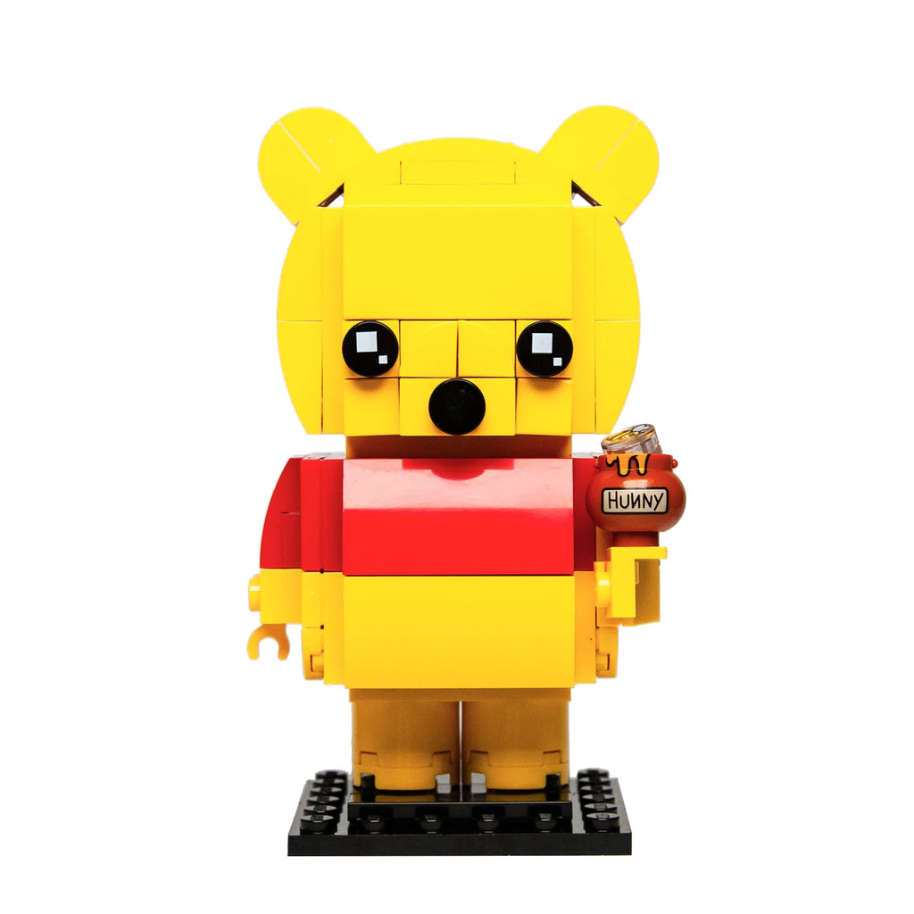 Custom Lego BrickHeadz rendition of Pooh Bear in yellow and red, holding a honey pot, against a white backdrop.