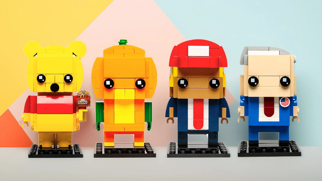 Image of Lego characters: A playful and colorful lineup of four Lego figures with a stylized design, each representing different characters. From left to right: a character in yellow and red holding a 'hunny' pot, a green and orange figure with a pen, a figure in red and blue sporting a cap, and a beige one with an American flag decal.