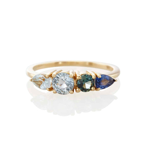 ombré ring from Vale Jewelry features a row of custom cut natural sapphires in a gradient of blues to create a beautiful harmony of colors with two round cuts and two pear cuts, set in 14K gold with prong-set sapphires