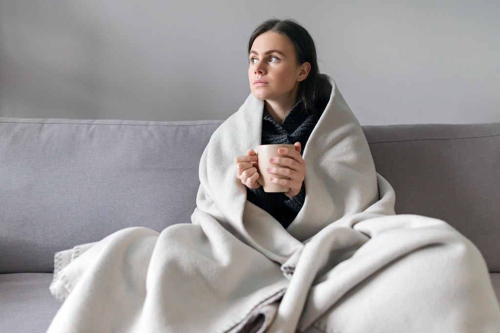 women with a fleece blanket on a sofa