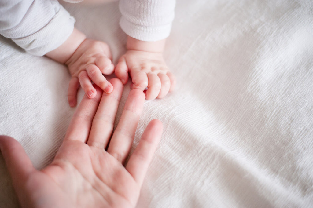 Hands of a newborn baby in the mother's fingers