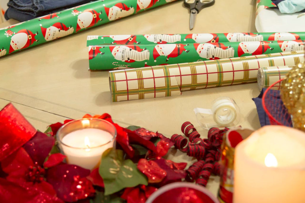 roll of wrapping papers, a scissor, a tape, and christmas decoration on a table