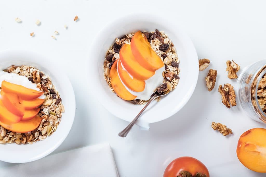 A healthy snack made of granola, yogurt, and peaches in a bowl. These ingredients together provide a mix of prebiotics and probiotics.