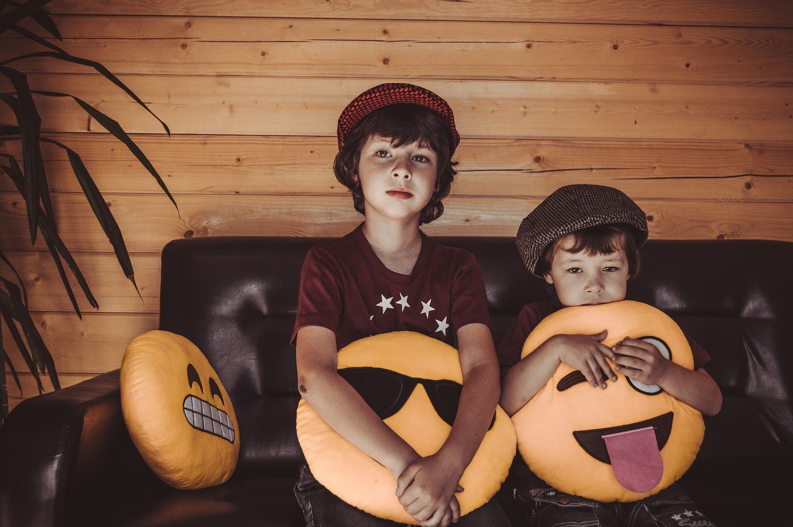 two-boys-sitting-on-sofa-holding-emoji-throw-pillows