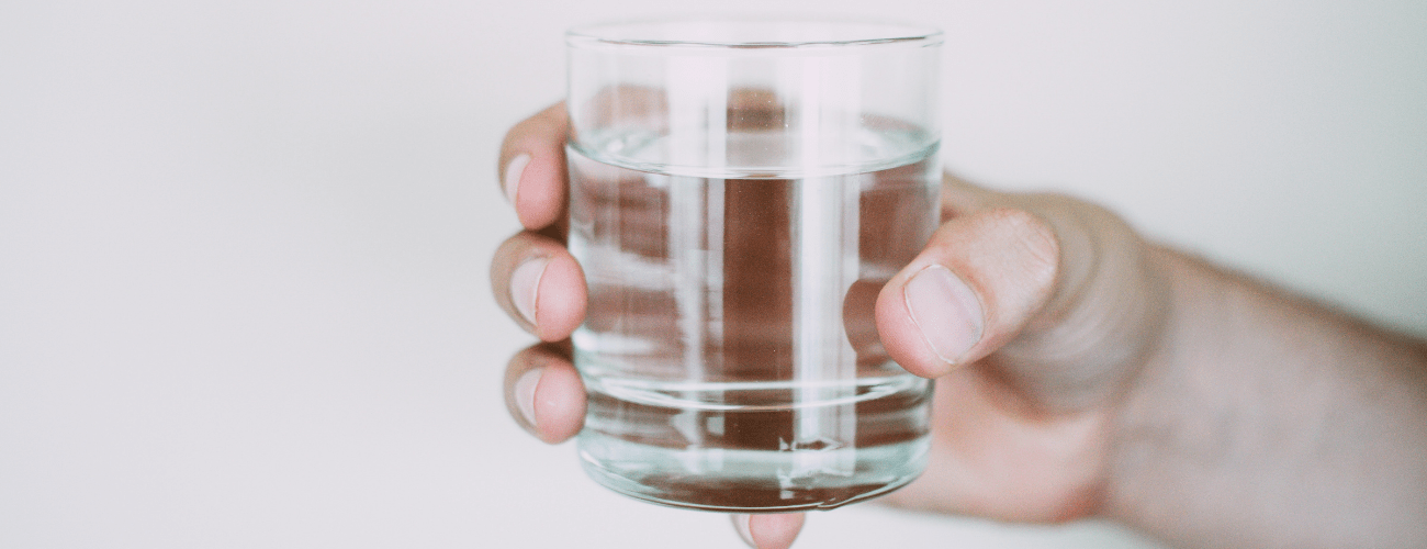 A hand holding a glass of water