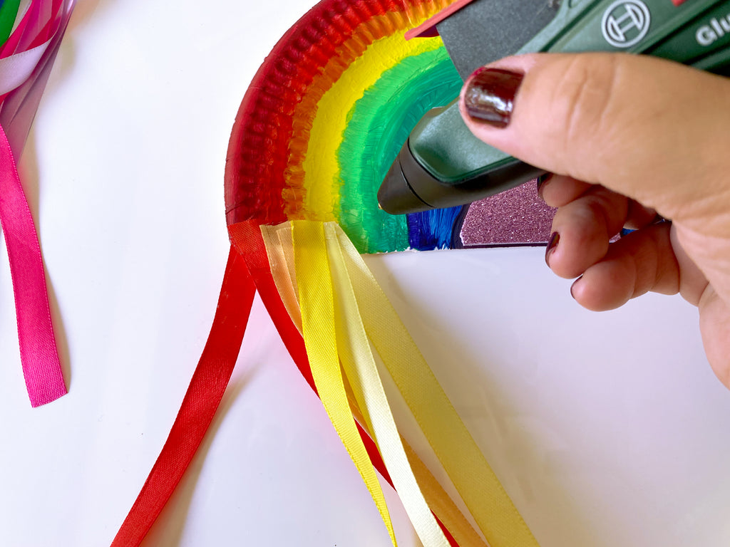 Satinbänder der Farbe nach auf den Regenbogen aufkleben