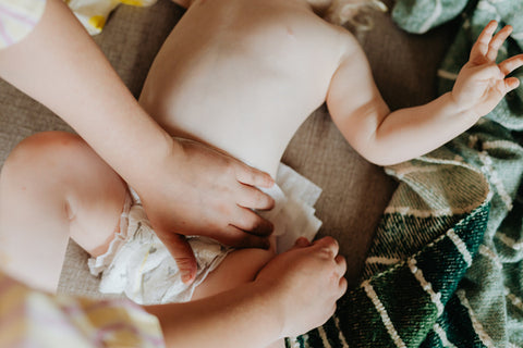 mani di mamma che cambiano pannolino a neonato