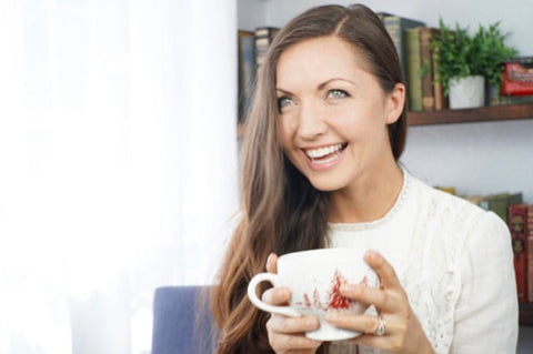 Rachael Bloome holding coffee mug in front of bookcase