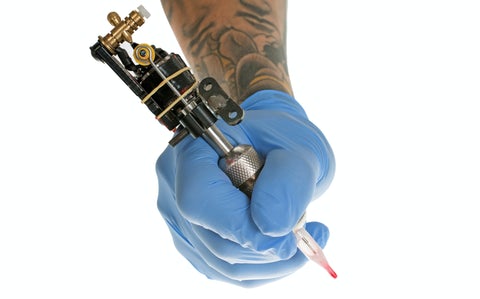 Gloved hand holding a tattoo gun