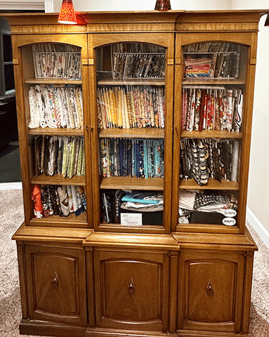 brown china cabinet filled with colorfull fabric