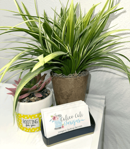 two faux plants and a stack of Calico Cali Designs business cards