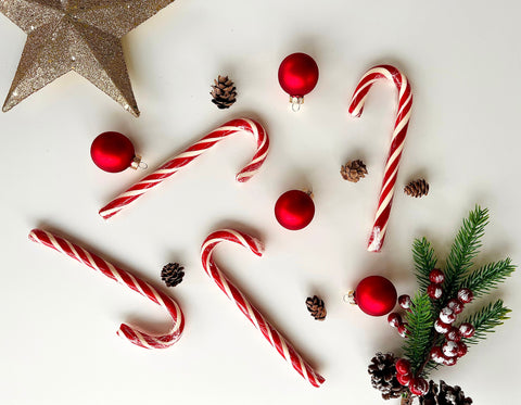 candy canes with red ornaments and greenery on a white background