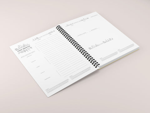 a spiral planner spread open on a pink background