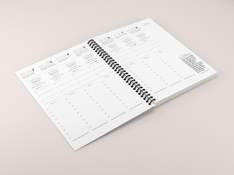 a spiral planner laid open on a pink background