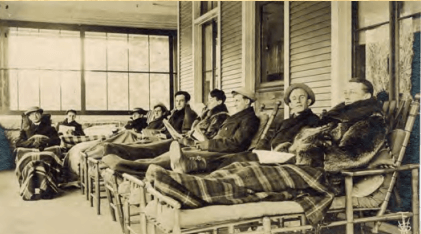 Men rest on cure chairs on porch (Historic Saranac Lake Collection)