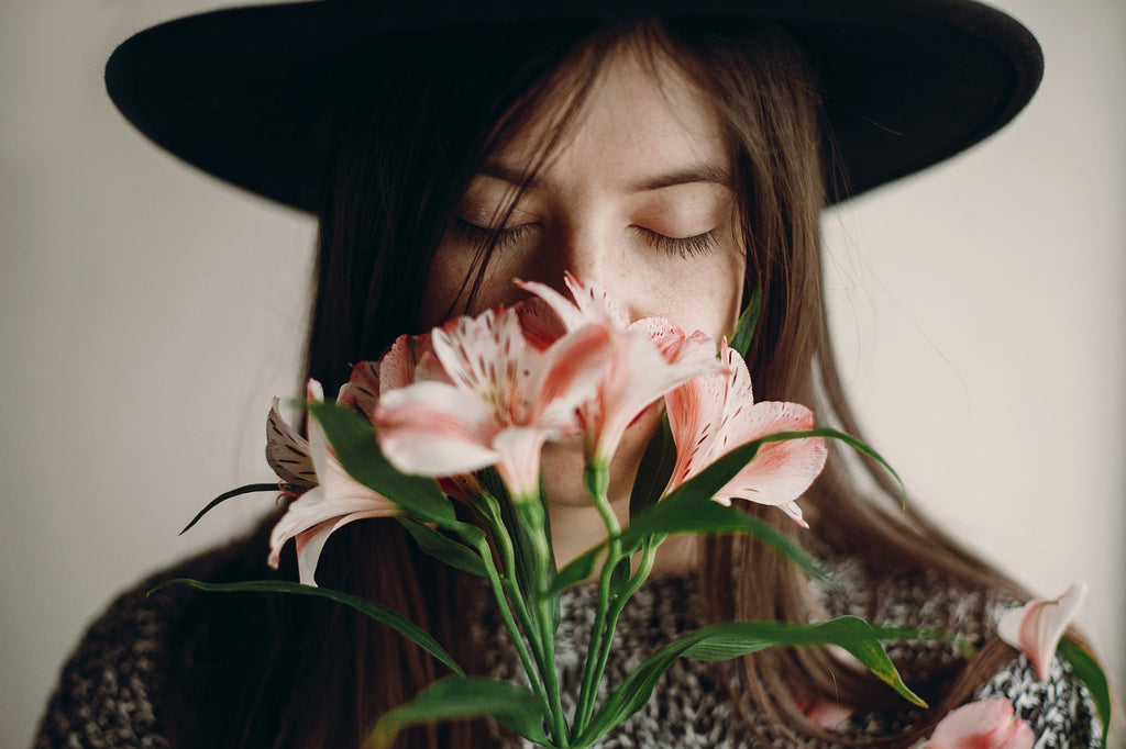 Uma moça cheirando uma flor. Será que fragrâncias naturais são mais seguras?