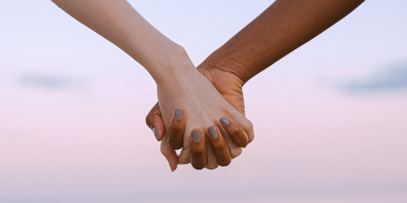 people holding hands in front of sunset