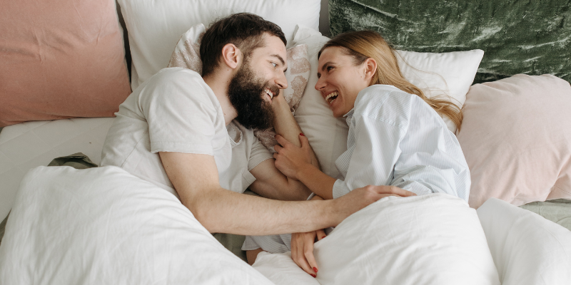 Smiling couple lying in bed together post sex