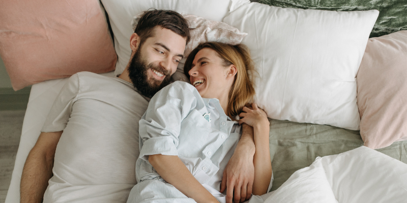 man and woman in bed cuddling 