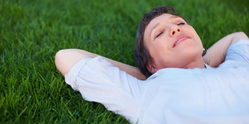 Menopausal woman lying on grass relaxing