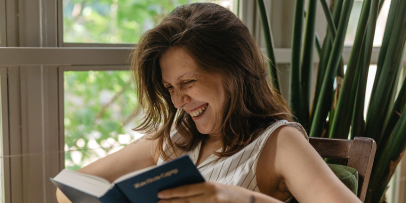 woman laughing and enjoying book