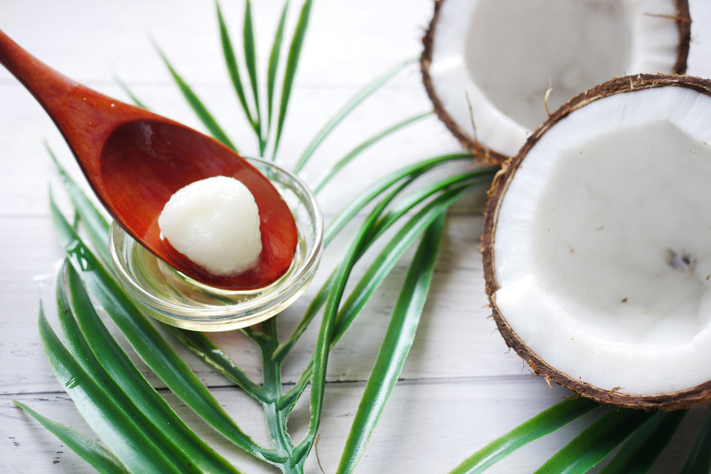 coconut cut in half next to spoon and leaves